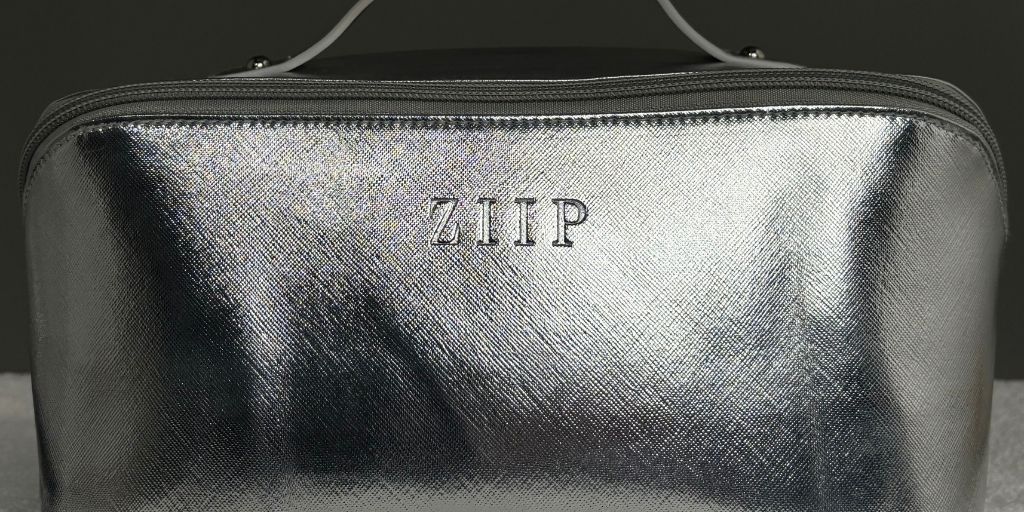 Close-up of the metallic silver travel pouch included with the ZIIP Superior Set, showing the embossed logo and zipper detail.
