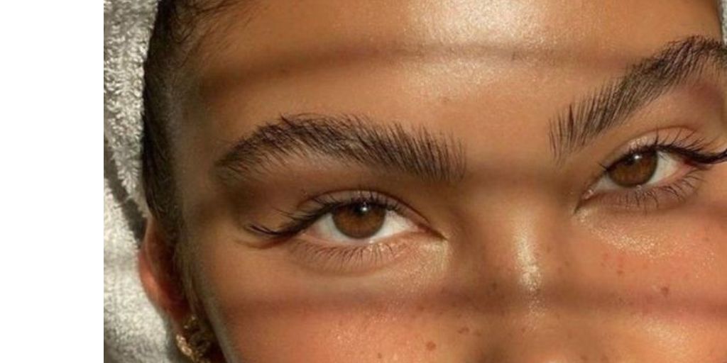 Close-up beauty shot of a woman's eyes, brows, and upper cheeks, showing smooth, dewy skin texture.